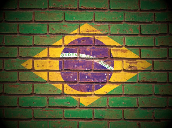 Bandeira do Brasil desgastada pintada sobre muro de tijolos, simbolizando desgaste democrático