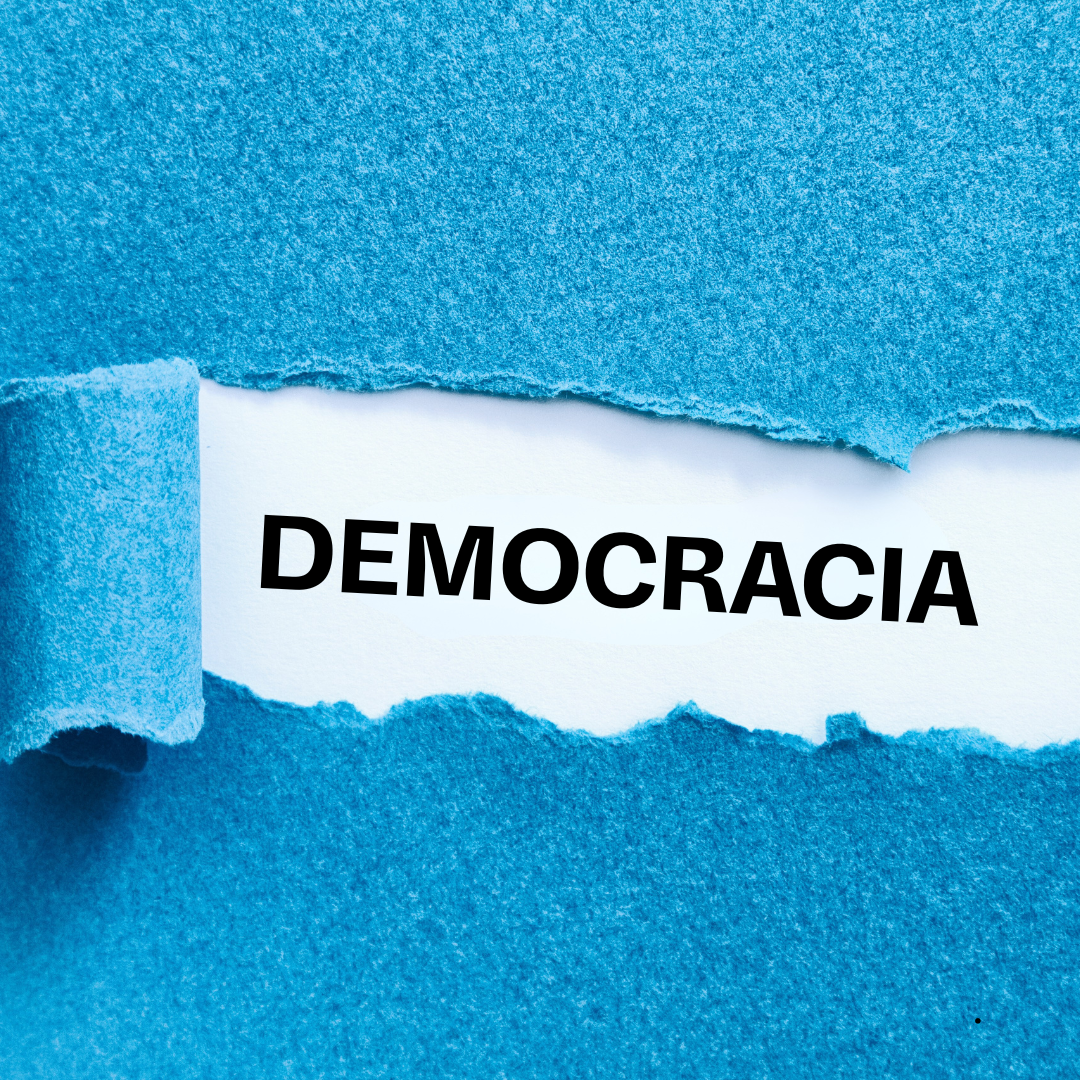 Papel azul rasgado revelando a palavra "DEMOCRACIA" em fundo branco.